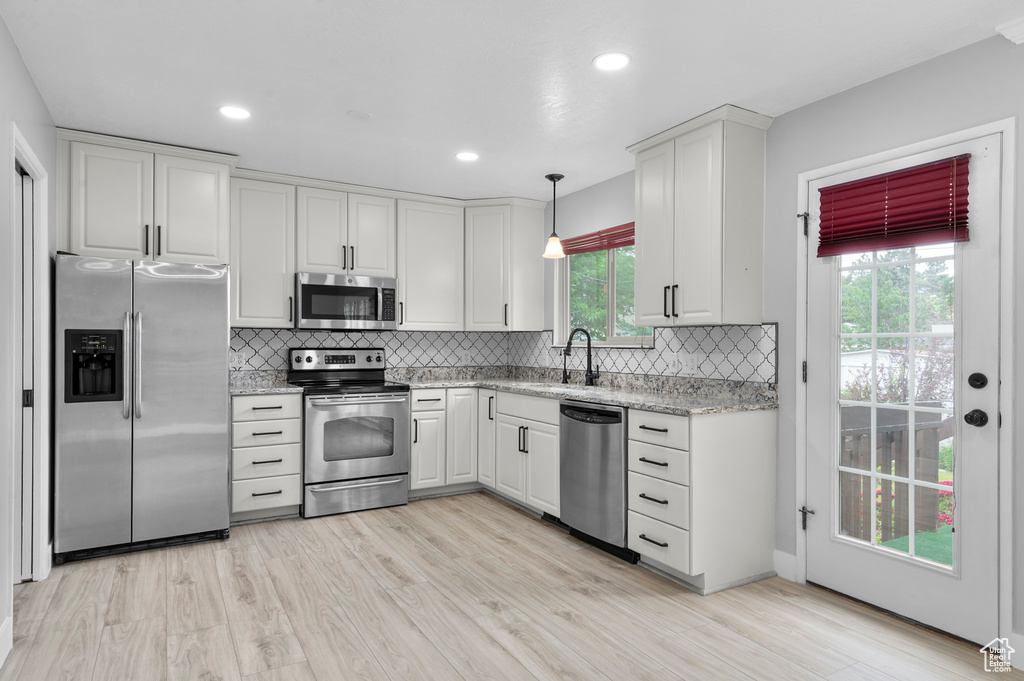 Kitchen featuring stainless steel appliances, white cabinets, backsplash, and recessed lighting