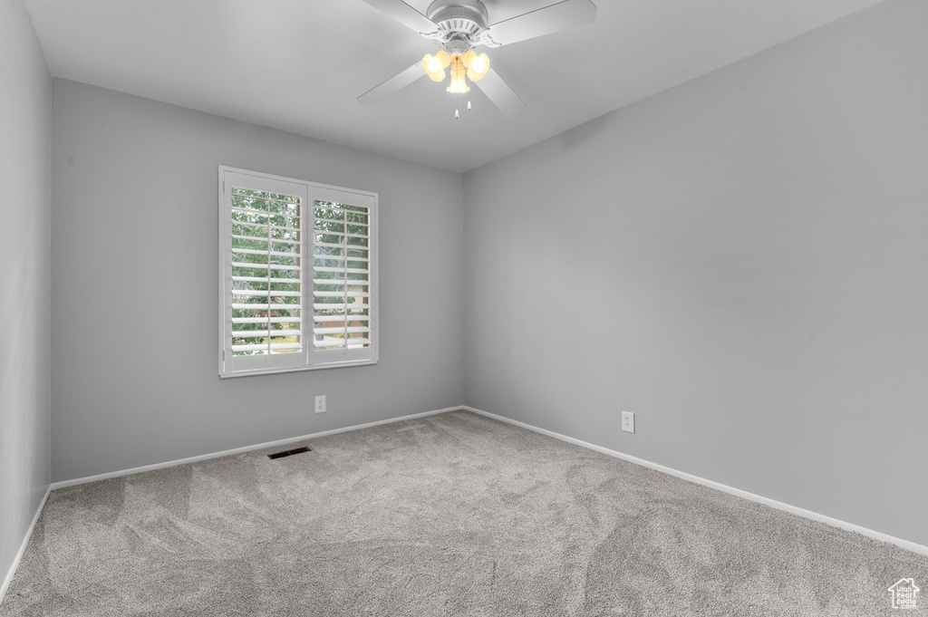 Carpeted spare room featuring a ceiling fan and baseboards
