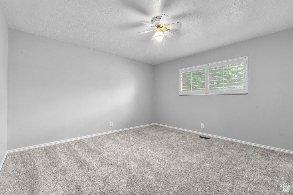 Unfurnished room with ceiling fan, a textured ceiling, and carpet flooring