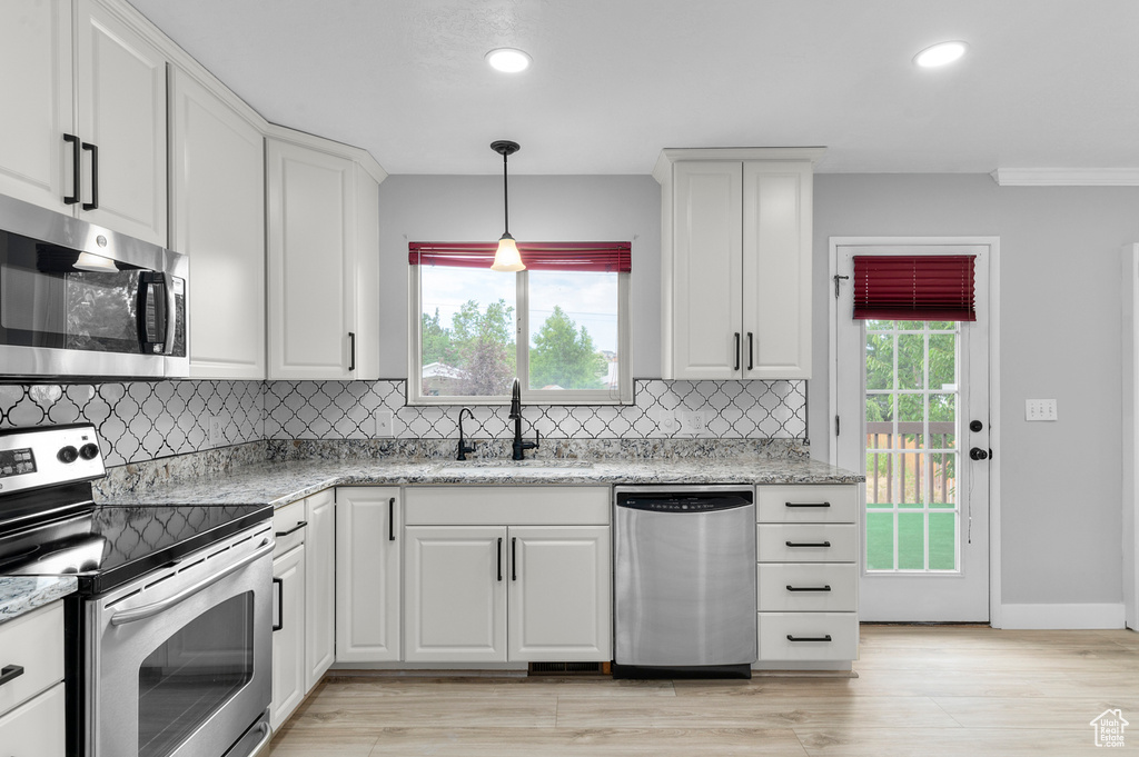 Kitchen featuring stainless steel appliances, recessed lighting, white cabinetry, backsplash, and decorative light fixtures