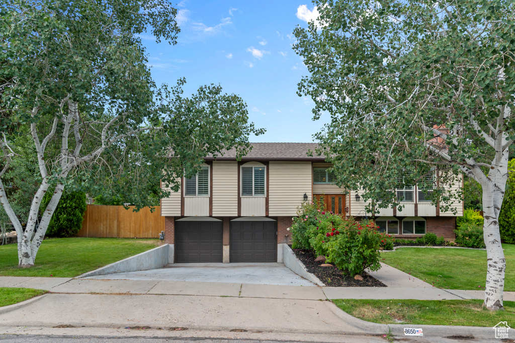 Split foyer home featuring brick siding, a garage, concrete driveway, and a shingled roof