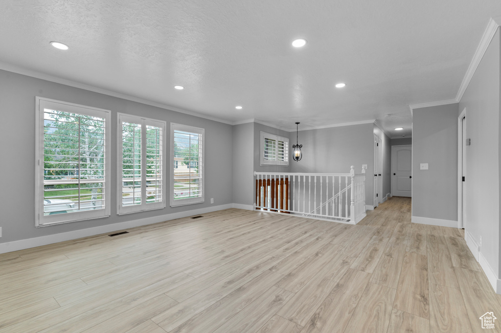 Empty room with ornamental molding, light wood-style flooring, and recessed lighting