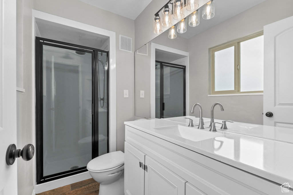Full bath featuring a shower stall, vanity, and wood finished floors