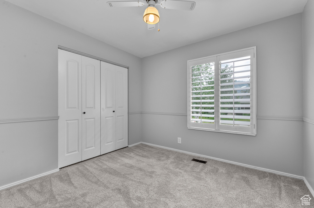 Unfurnished bedroom featuring carpet flooring, a closet, and ceiling fan