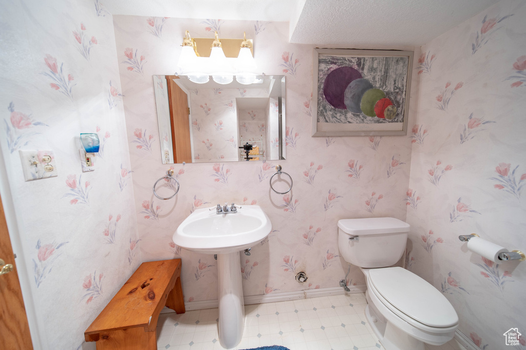 Half bathroom featuring tile patterned floors and wallpapered walls