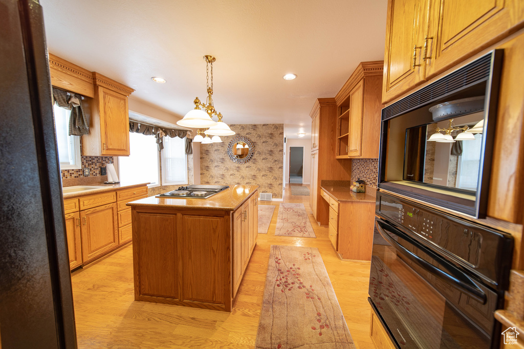 Kitchen featuring oven, a kitchen island, light countertops, light wood-style floors, and recessed lighting