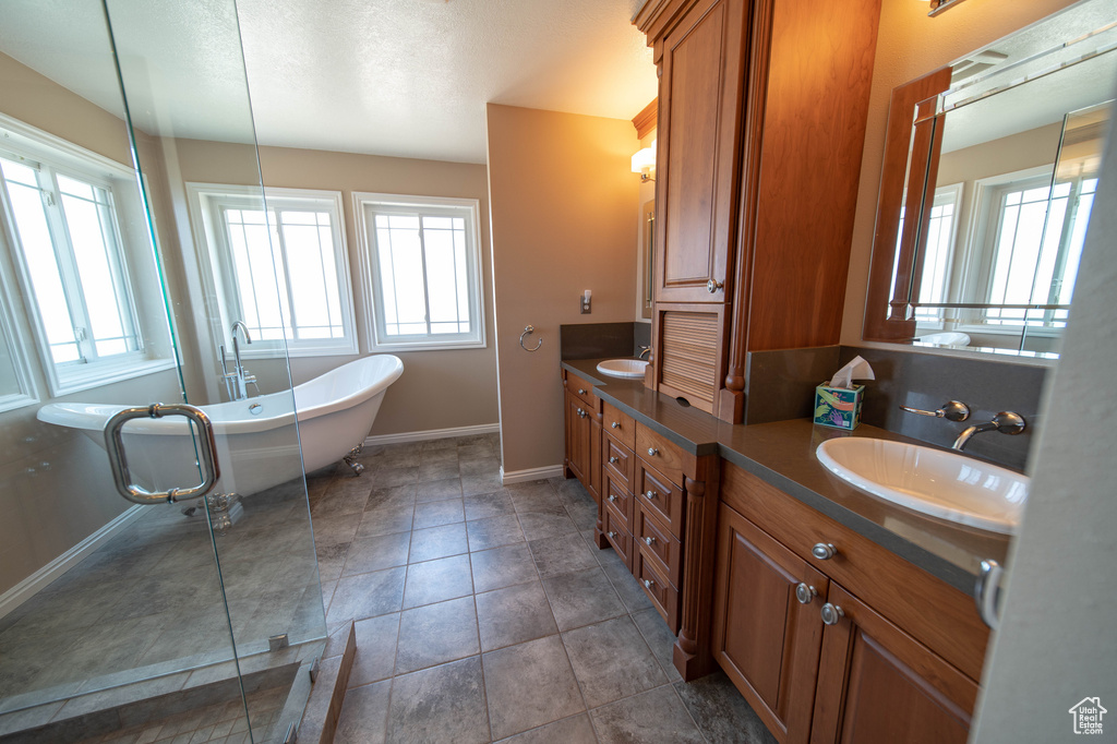 Full bathroom featuring double vanity, a freestanding bath, and tile patterned floors