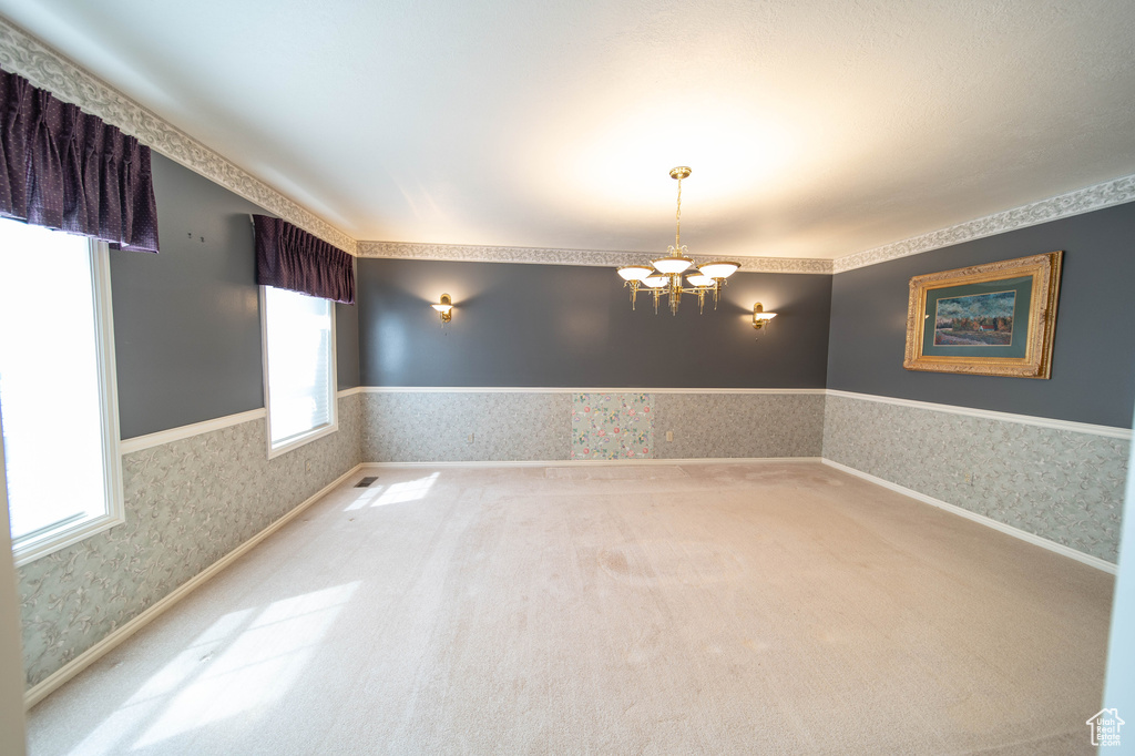 Spare room with wallpapered walls, a chandelier, and carpet floors