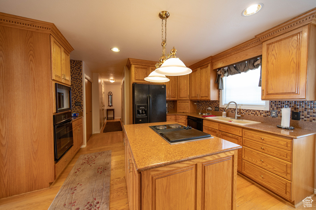Kitchen with black appliances, a center island, tasteful backsplash, light wood-style flooring, and recessed lighting