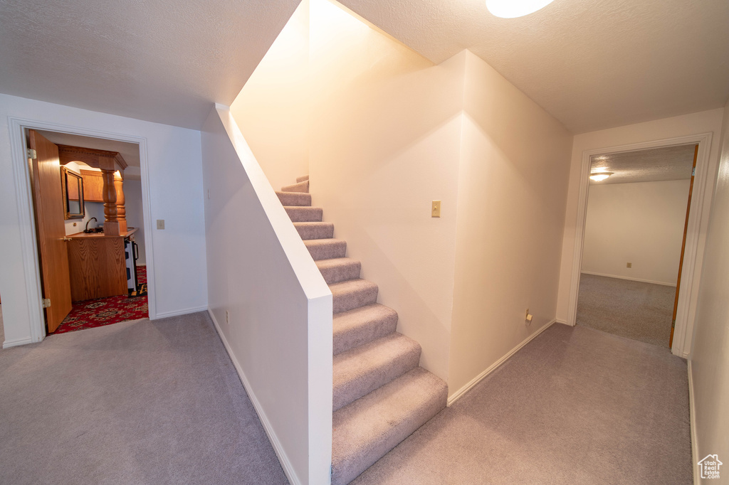 Stairs featuring carpet floors and a textured ceiling