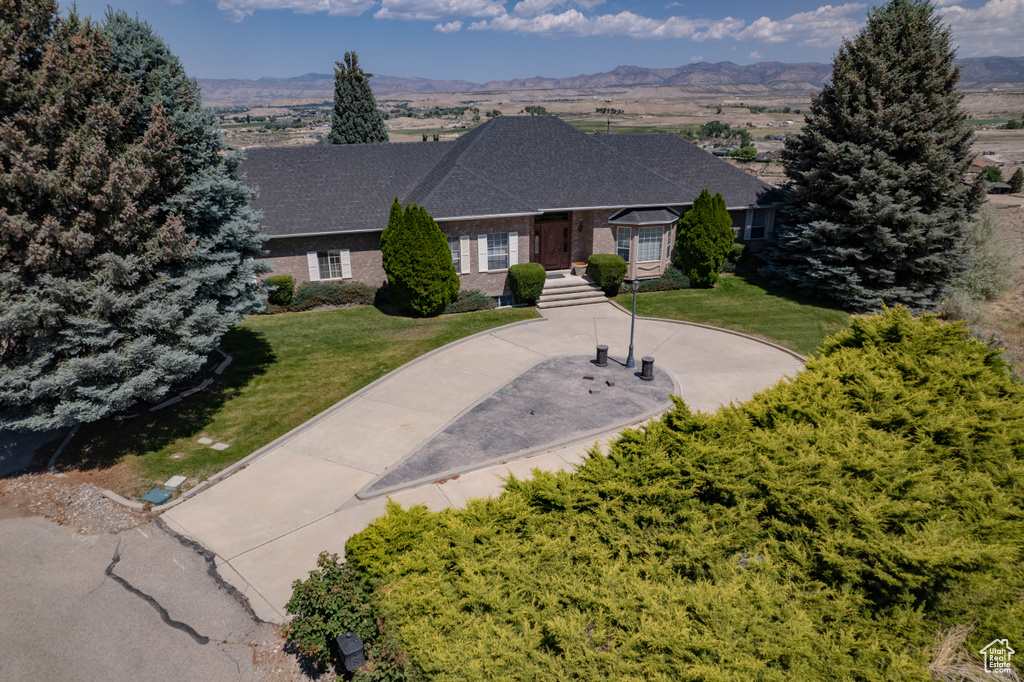 Ranch-style house with a front yard, a mountain view, and brick siding
