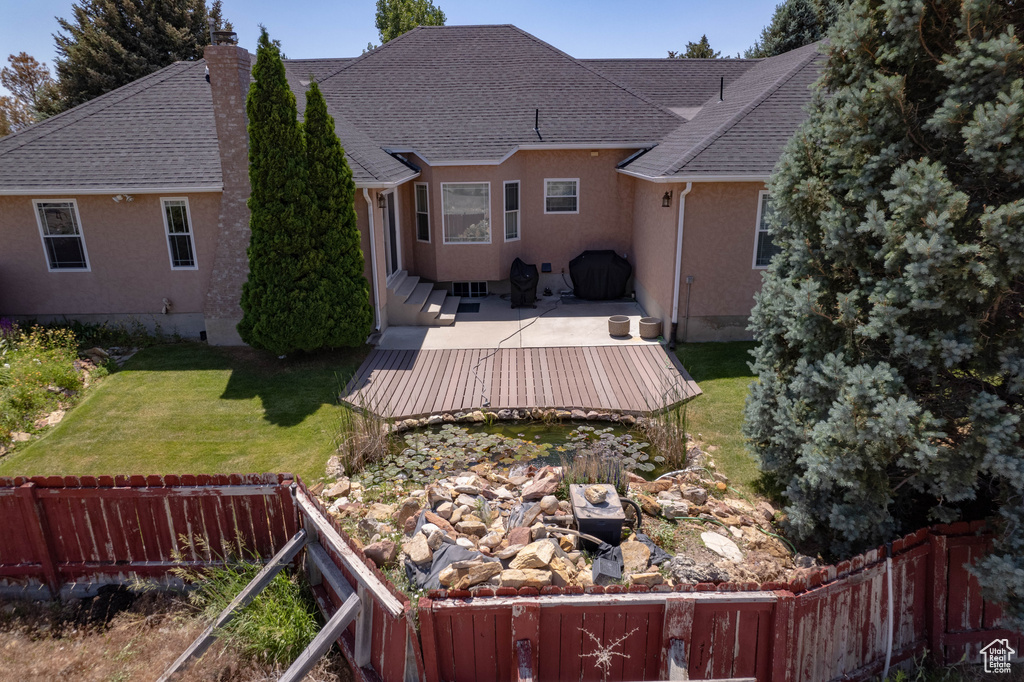 Back of house with a deck, a chimney, stucco siding, and roof with shingles