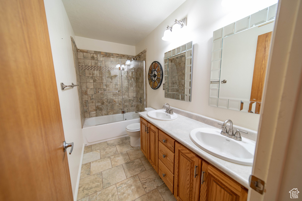Full bathroom with double vanity, shower / bath combination, and stone finish floors