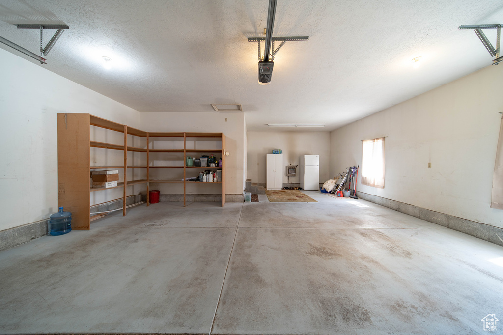 Garage featuring freestanding refrigerator and a garage door opener