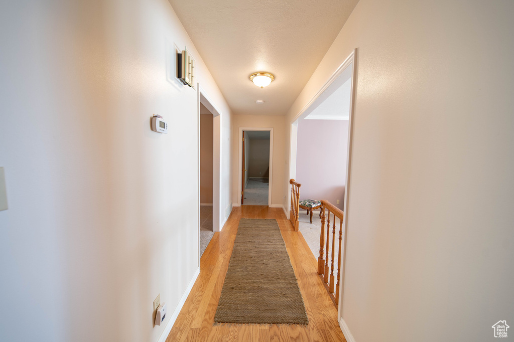 Corridor with light wood-style flooring and an upstairs landing
