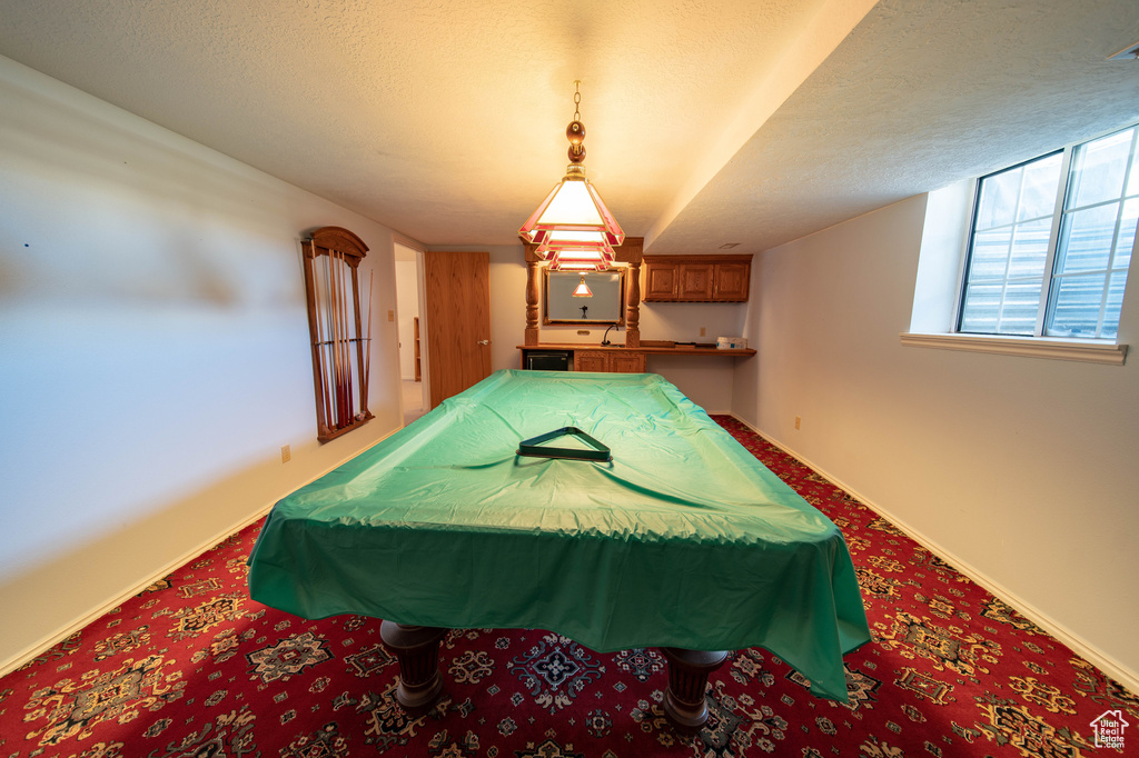 Game room with carpet floors, billiards table, and a textured ceiling