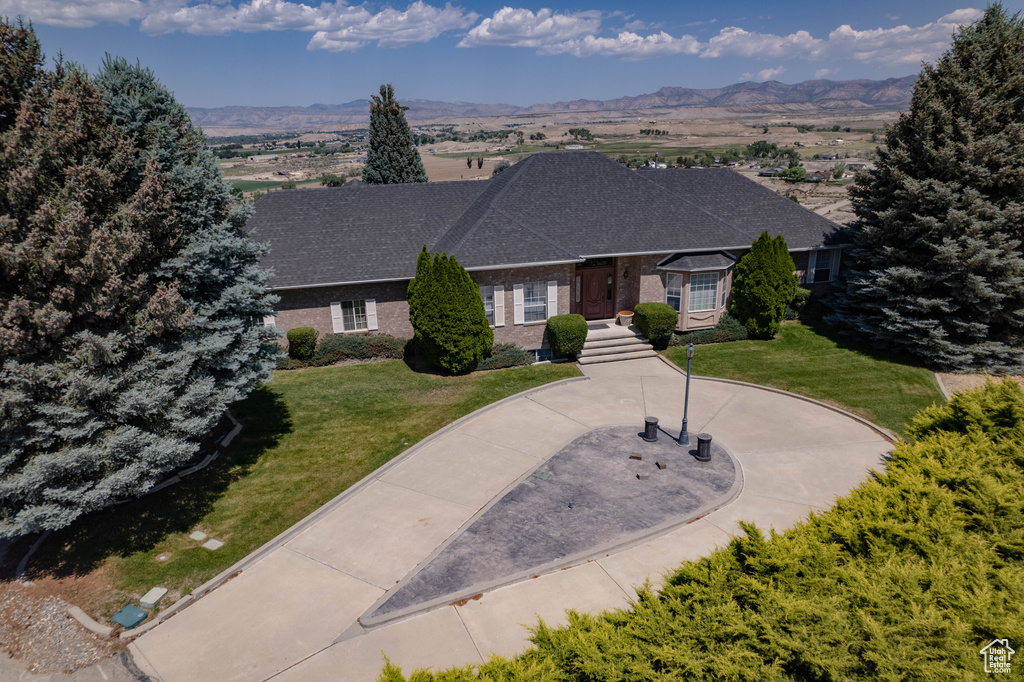 View of front facade with a mountain view, a front yard, and brick siding