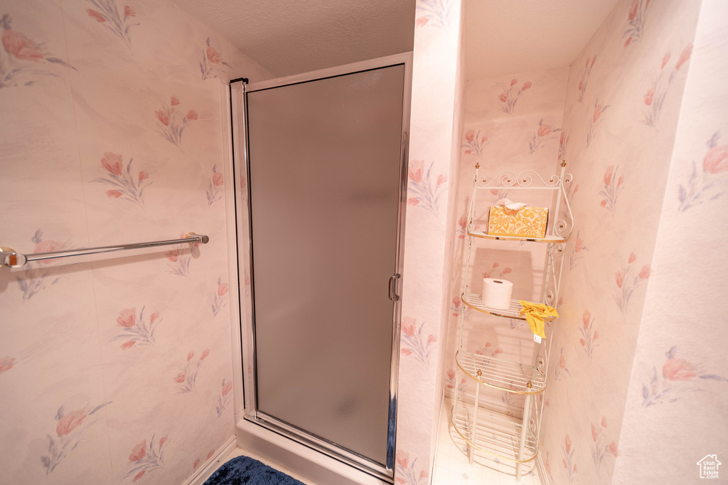 Full bathroom featuring a shower stall and wallpapered walls