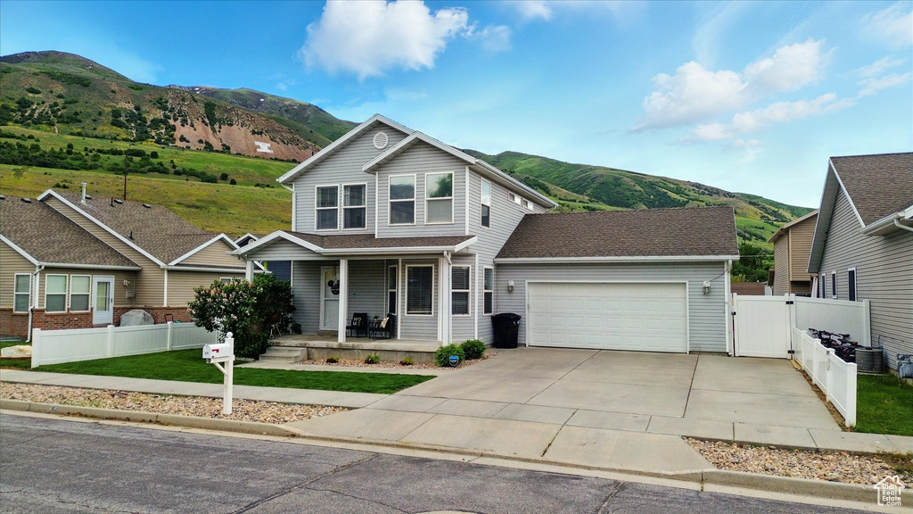 Traditional-style house featuring a mountain view, covered porch, an attached garage, a gate, and driveway