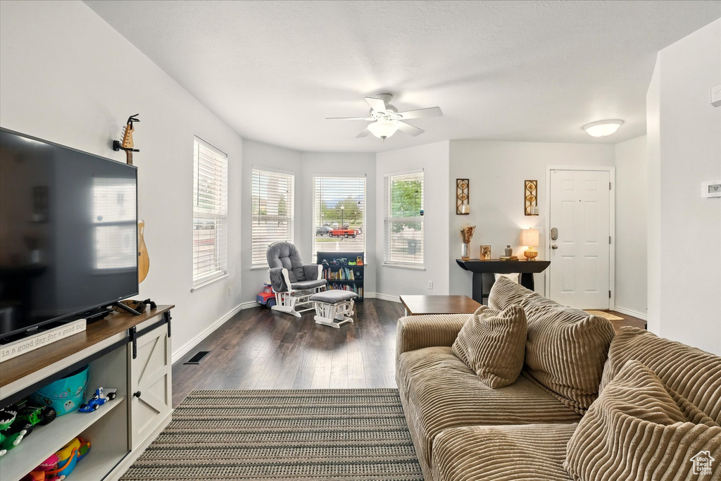 Living area with ceiling fan and dark wood-style flooring