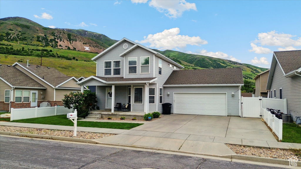 Traditional home with a mountain view, a porch, a gate, and an attached garage