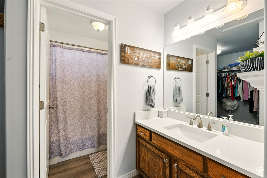 Full bath featuring vanity, a spacious closet, wood finished floors, and a shower with shower curtain
