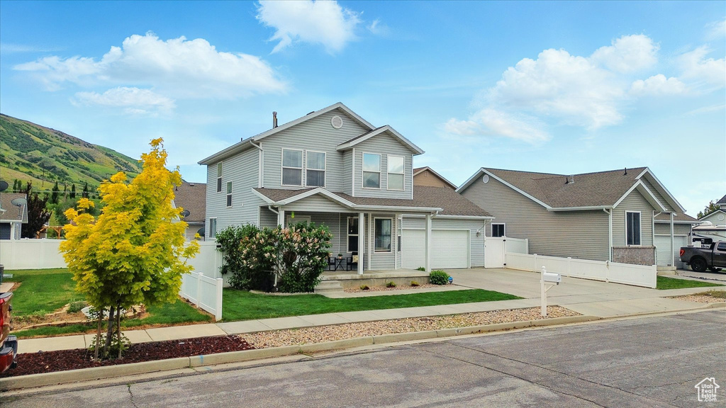 View of front facade with covered porch, concrete driveway, and an attached garage
