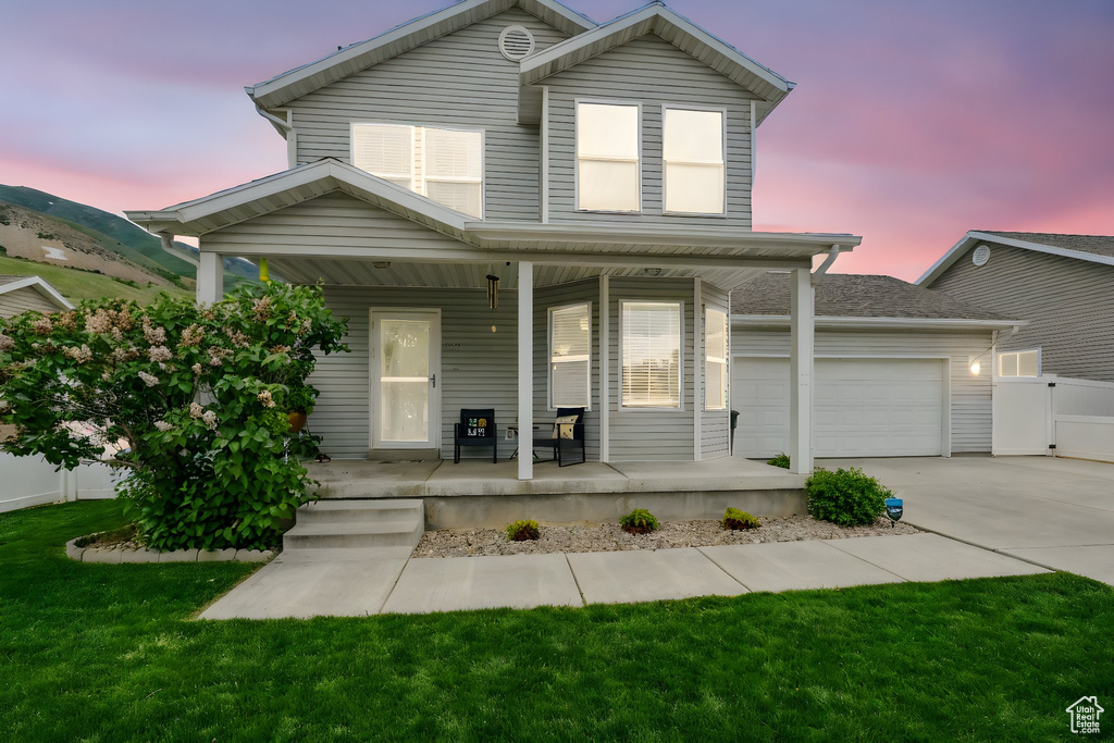 Traditional-style home with covered porch, concrete driveway, and a garage