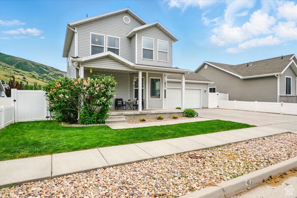 Traditional-style home featuring covered porch, concrete driveway, a garage, a gate, and a mountain view