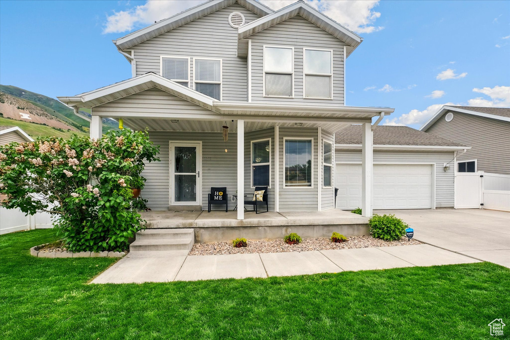 Traditional-style house with covered porch, driveway, and an attached garage