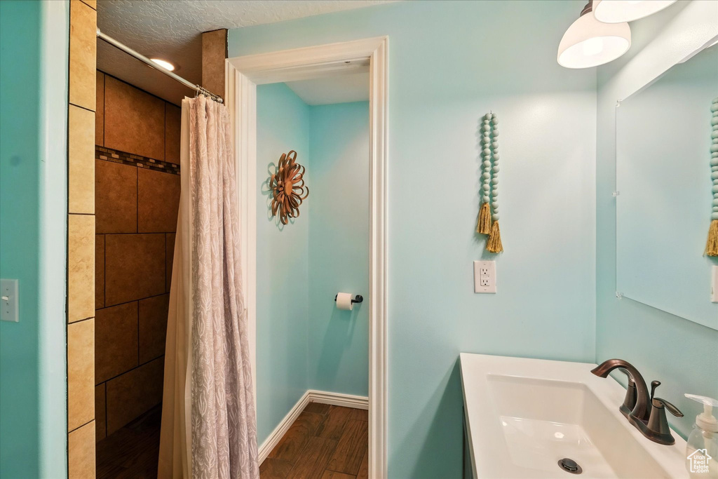 Full bathroom with a tile shower, wood finished floors, and vanity