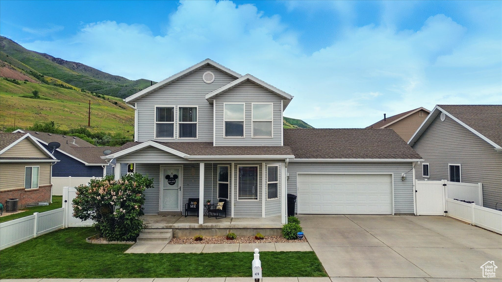 Traditional-style home featuring a porch, an attached garage, concrete driveway, a mountain view, and a gate
