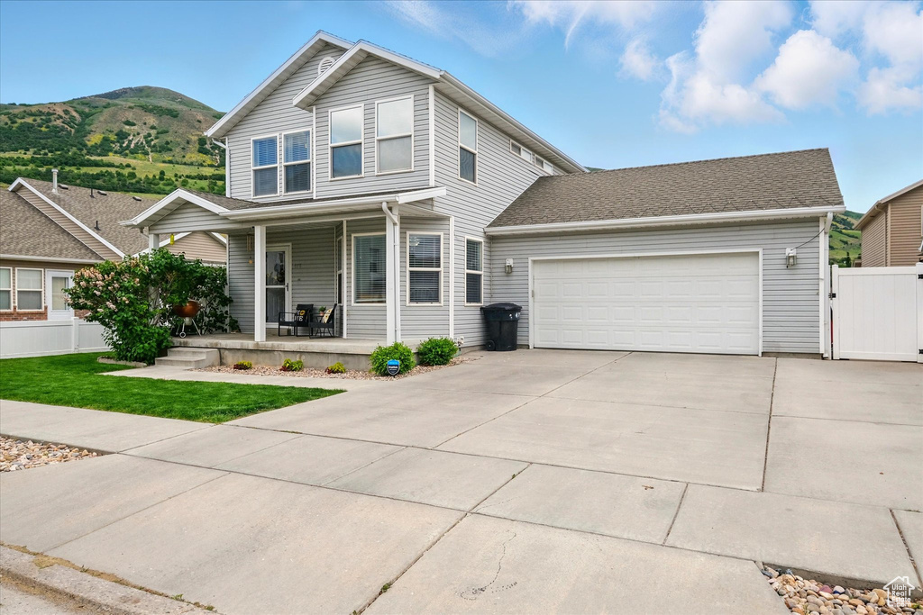 View of front of property with a porch, an attached garage, driveway, a mountain view, and a gate
