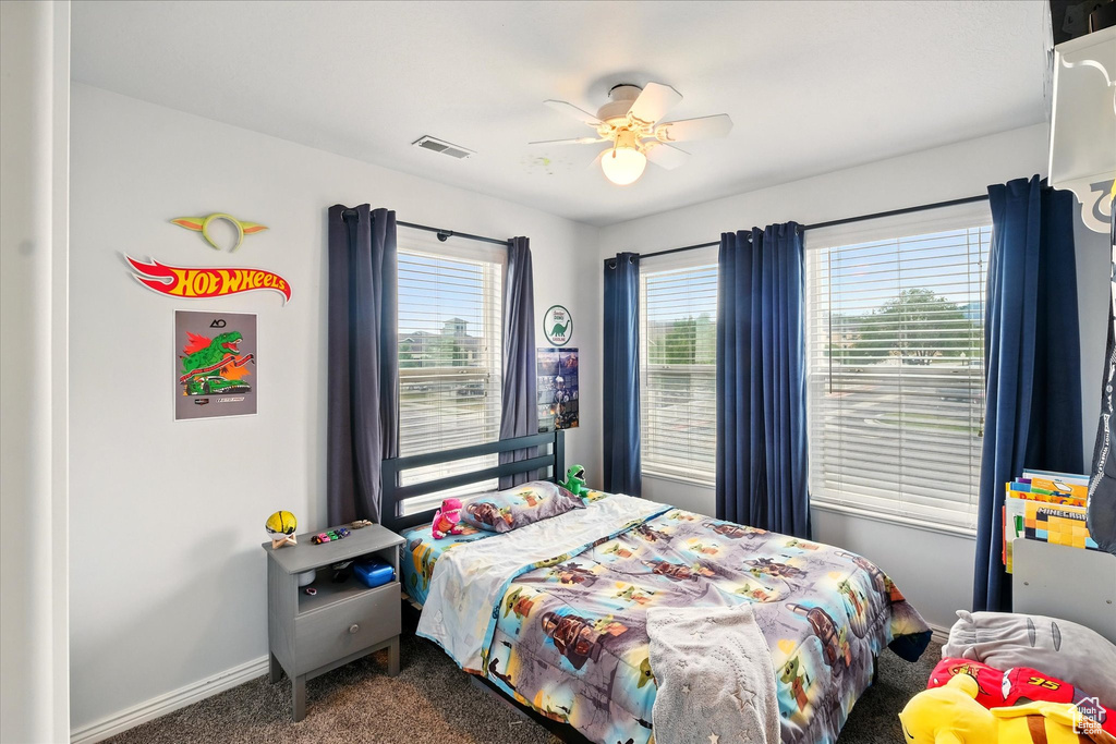 Bedroom with dark colored carpet and a ceiling fan