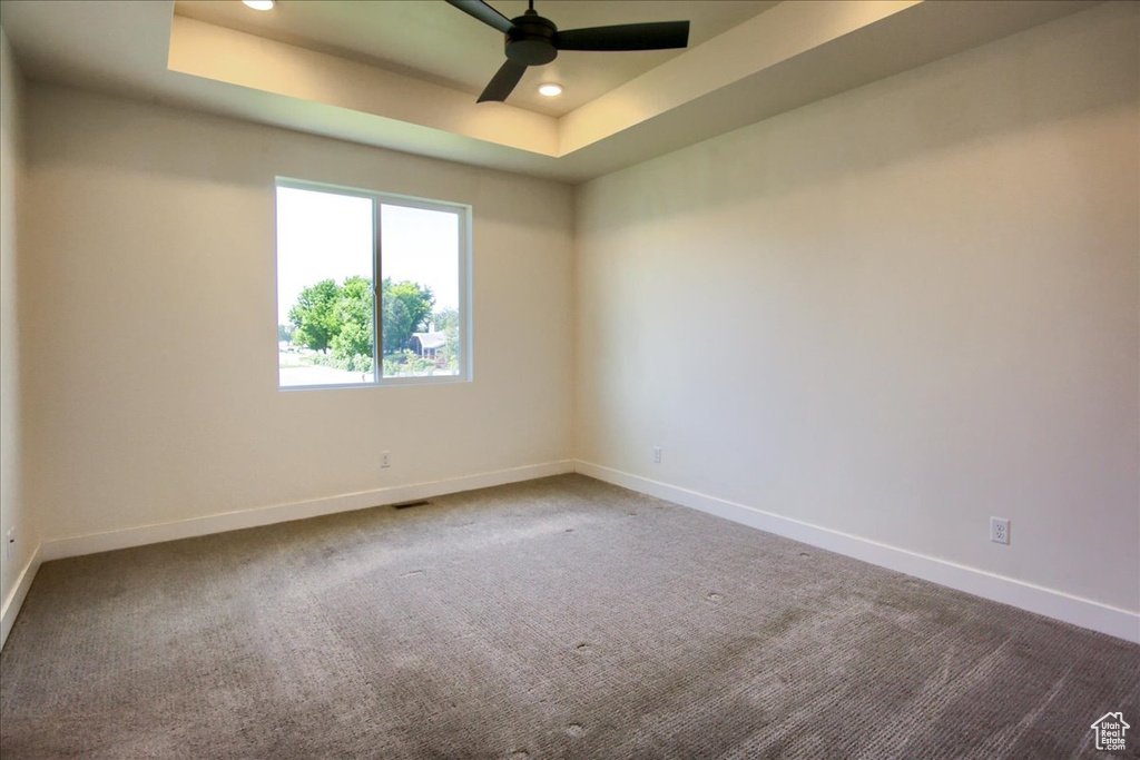 Carpeted spare room featuring a raised ceiling, a ceiling fan, and recessed lighting