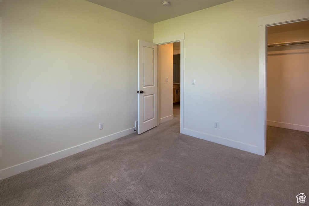 Unfurnished bedroom featuring carpet flooring, a closet, and a walk in closet