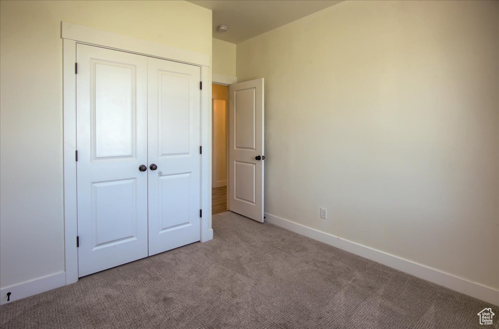 Unfurnished bedroom with light carpet and a closet