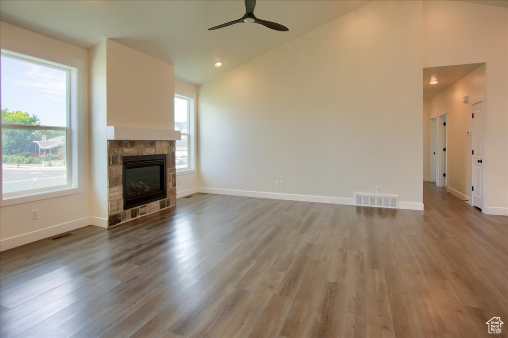 Unfurnished living room with lofted ceiling, ceiling fan, wood finished floors, a stone fireplace, and recessed lighting