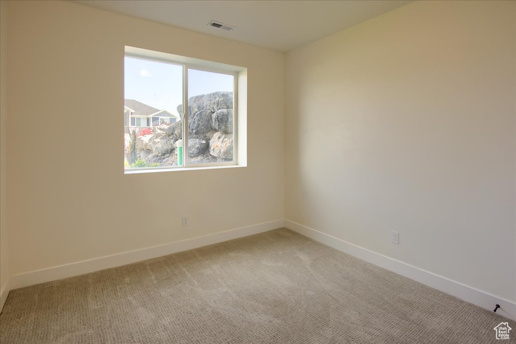 Empty room with light colored carpet and baseboards