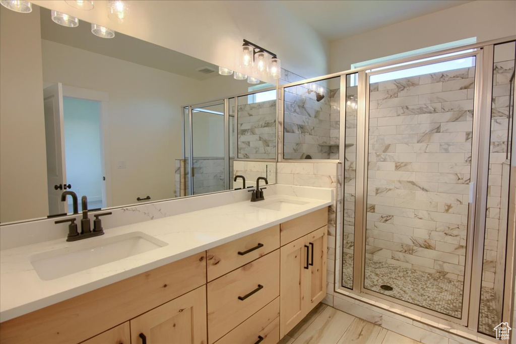Full bath featuring a stall shower, double vanity, and wood finished floors