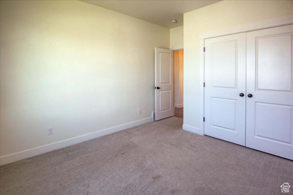 Unfurnished bedroom featuring light colored carpet and a closet