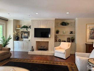 Living room featuring wood finished floors, a large fireplace, recessed lighting, and ornamental molding