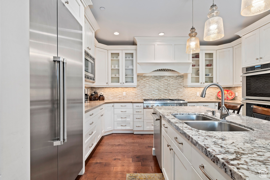 Kitchen with stainless steel appliances, decorative light fixtures, light stone counters, white cabinets, and recessed lighting