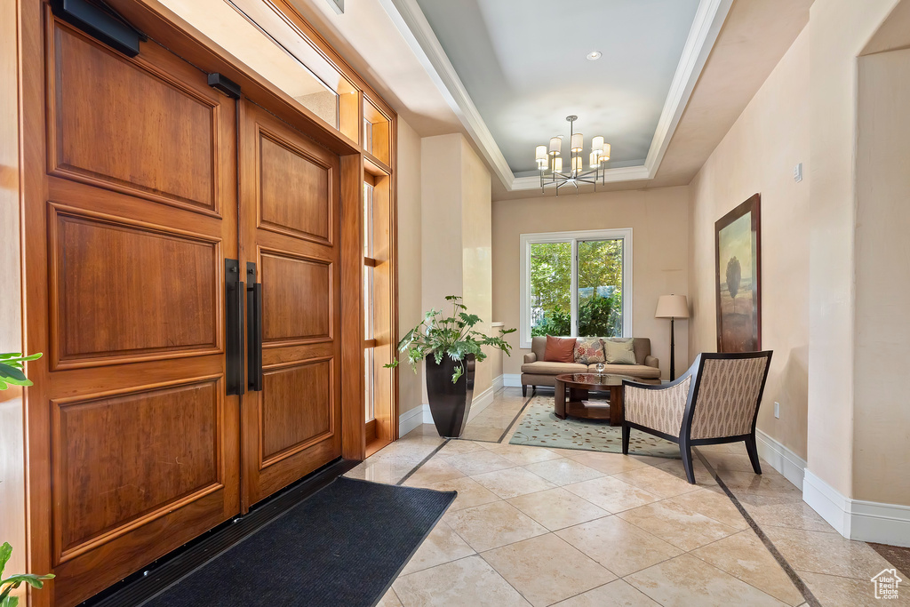 Foyer with a raised ceiling, a chandelier, and light tile patterned flooring