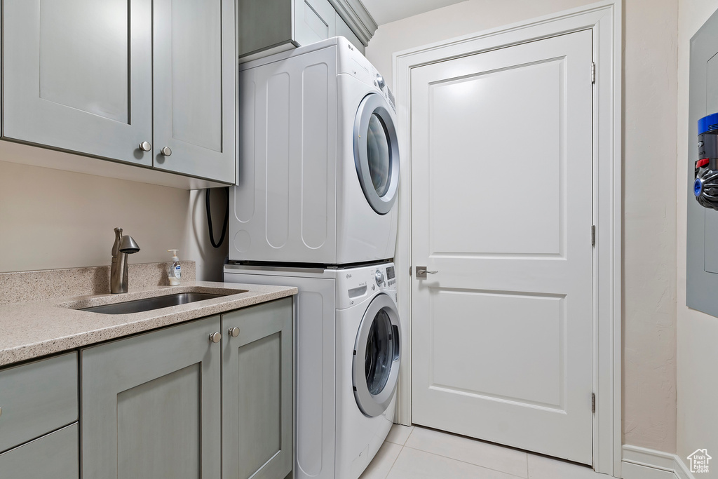 Washroom with stacked washer / dryer, cabinet space, and light tile patterned floors