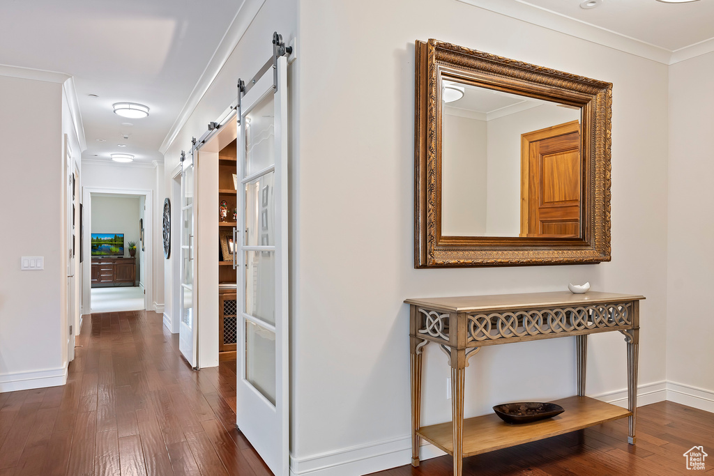 Hallway featuring a barn door, dark wood-style floors, and crown molding