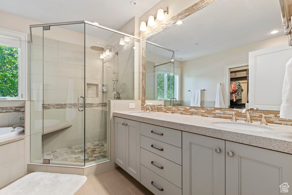 Bathroom with double vanity, a stall shower, tile patterned floors, tasteful backsplash, and a spacious closet
