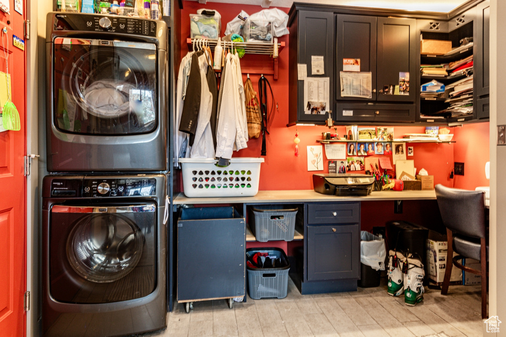 Washroom with stacked washer and clothes dryer, wood finished floors, and a desk