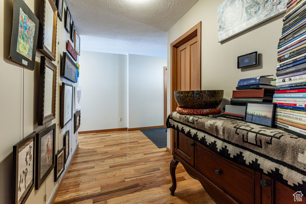 Corridor with light wood-style floors and a textured ceiling
