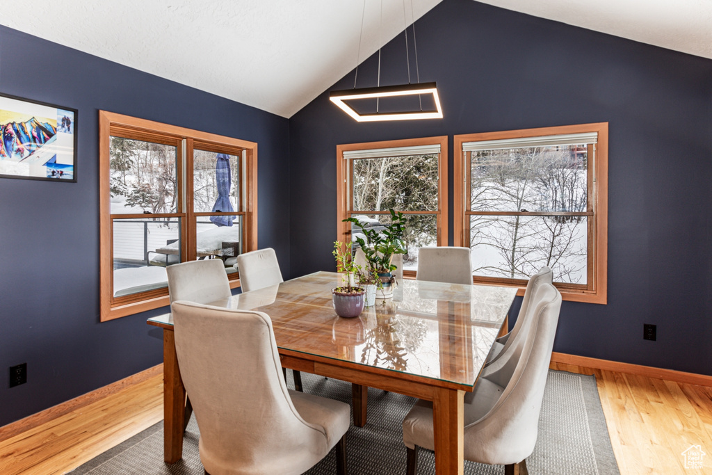 Dining space with wood finished floors, healthy amount of natural light, and lofted ceiling